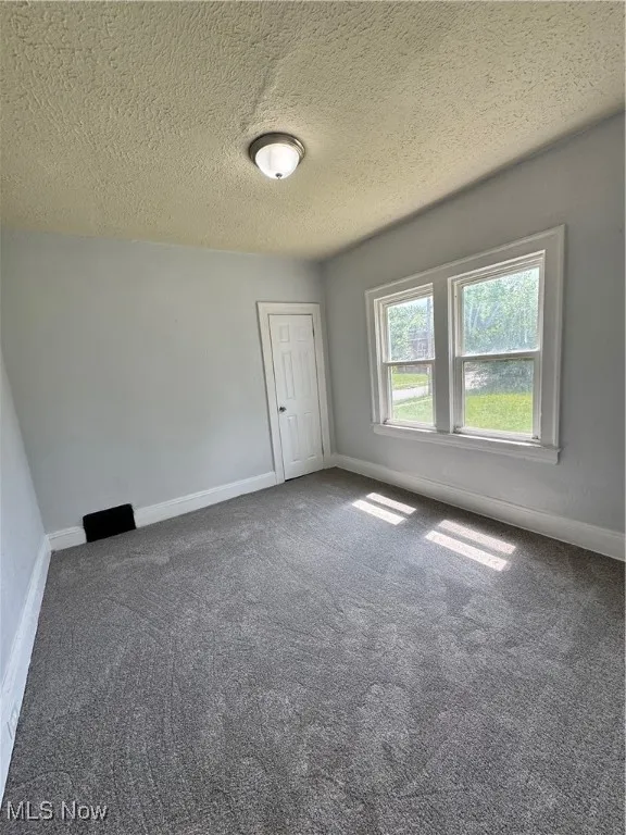 Empty room with carpet floors and a textured ceiling