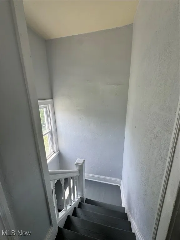 Staircase featuring a textured wall and wood finished floors
