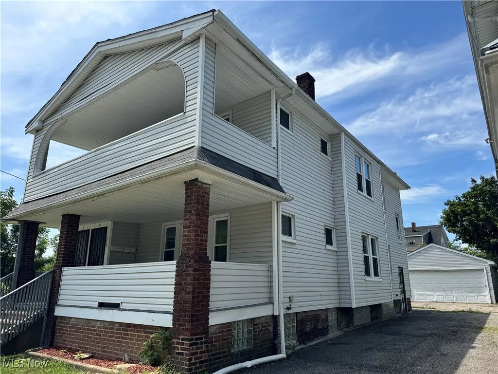View of side of home featuring a balcony, an outdoor structure, a chimney, and covered porch