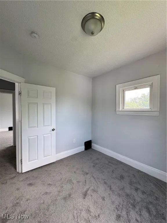 Unfurnished bedroom with carpet floors and a textured ceiling