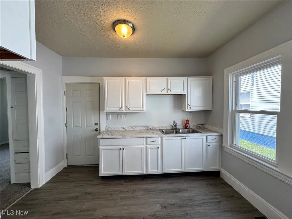 Kitchen featuring a textured ceiling, white cabinetry, light countertops, and dark wood finished floors