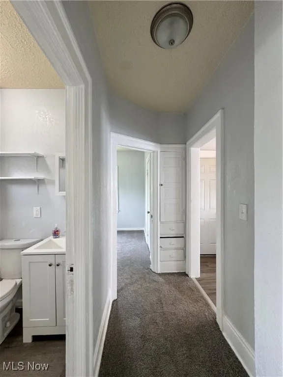 Hallway featuring a textured ceiling and carpet flooring