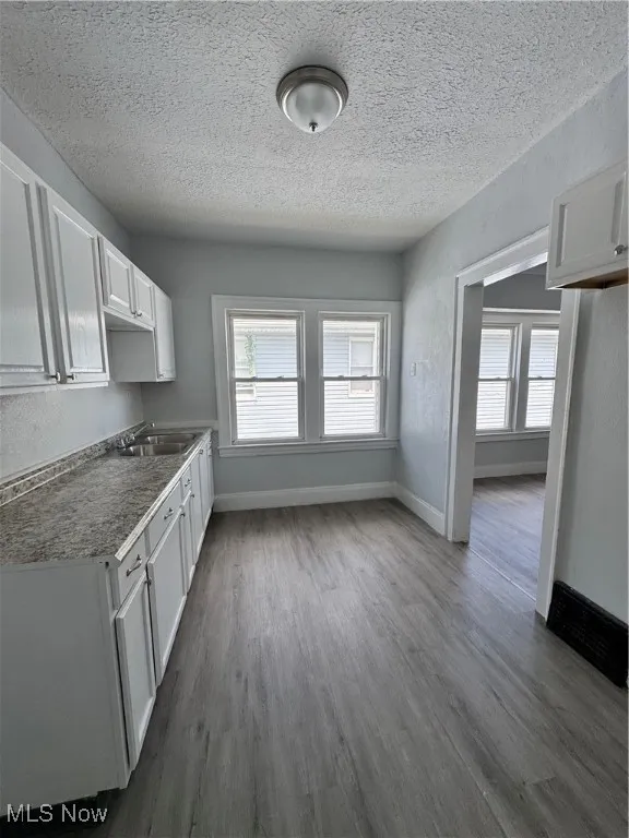 Kitchen featuring white cabinetry, dark wood-type flooring, and a textured ceiling
