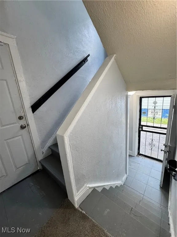 Staircase featuring a textured ceiling and a textured wall