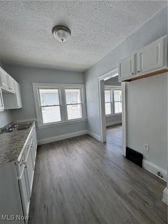Unfurnished dining area featuring dark wood-style floors and a textured ceiling