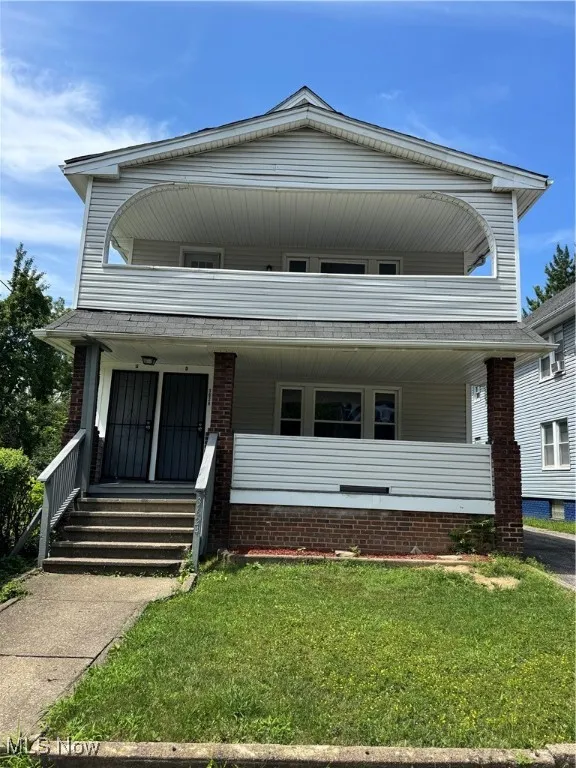 View of front facade featuring covered porch, a balcony, a front yard, and brick siding