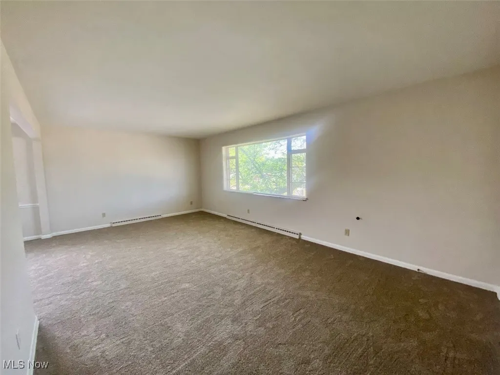 Empty room featuring carpet and baseboard heating