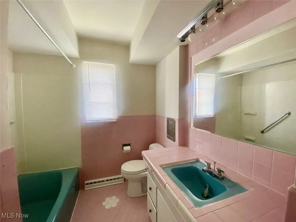 Bathroom with tile walls, plenty of natural light, vanity, a baseboard heating unit, and tile patterned flooring