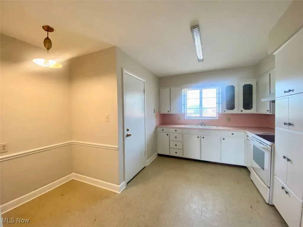 Kitchen featuring white range with electric cooktop, white cabinets, light flooring, under cabinet range hood, and light countertops