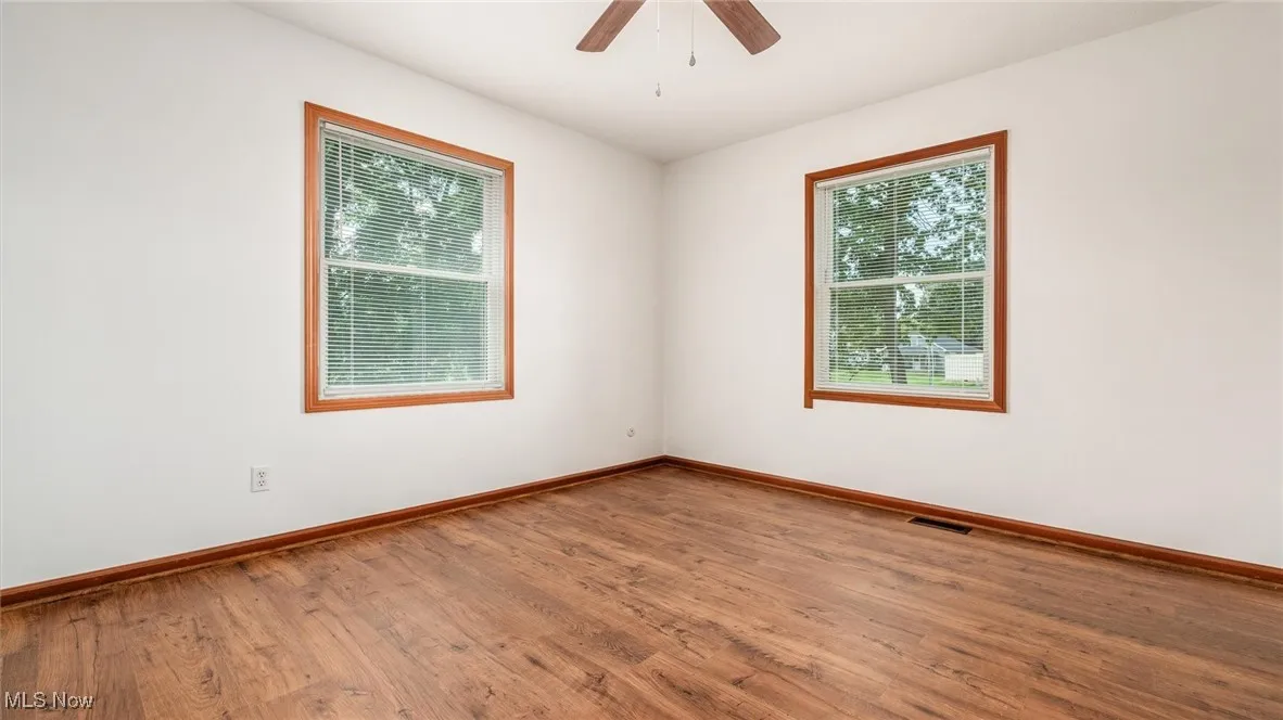 Unfurnished room with wood finished floors, healthy amount of natural light, and ceiling fan