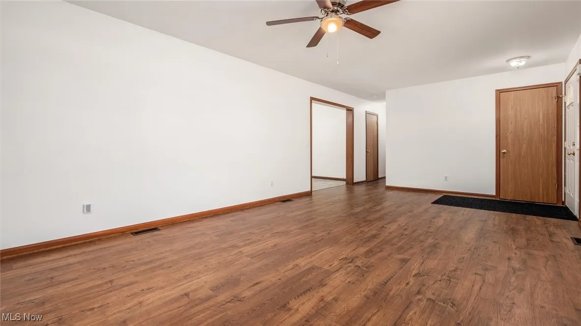 Spare room featuring ceiling fan and dark wood-style flooring