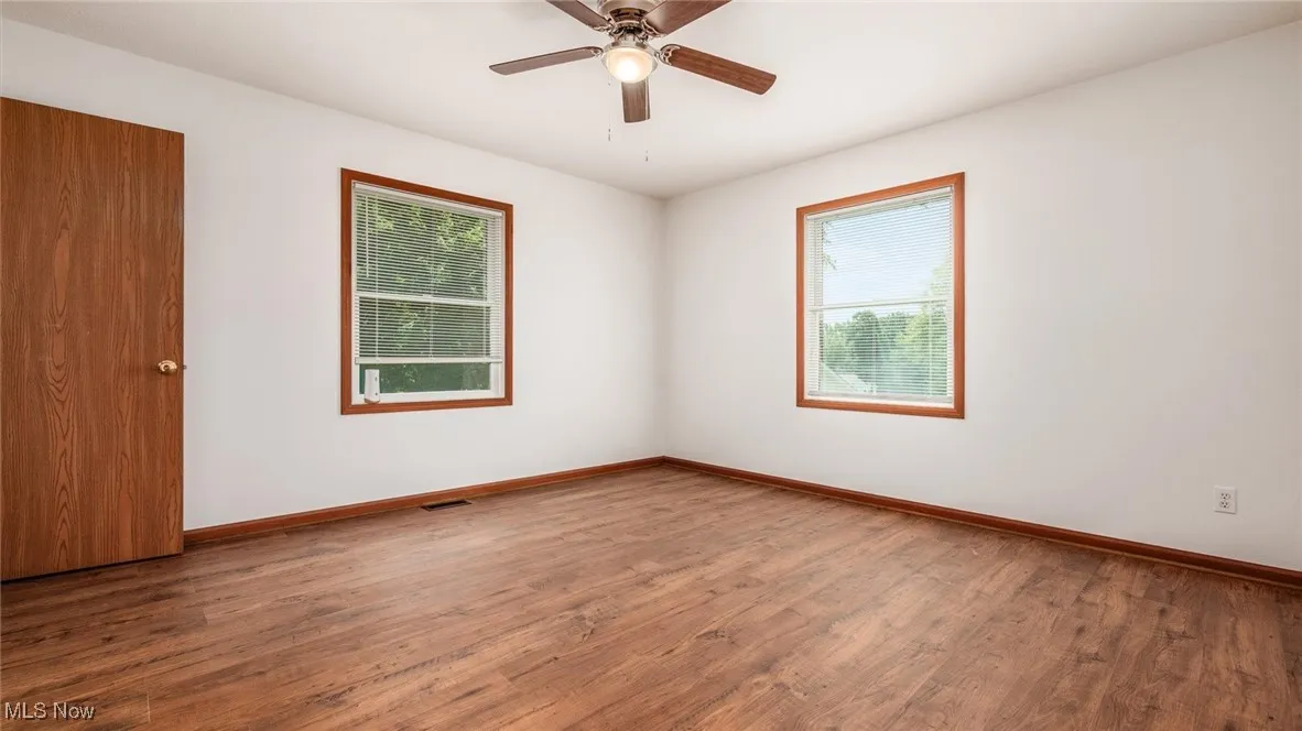 Unfurnished room featuring healthy amount of natural light, wood finished floors, and ceiling fan