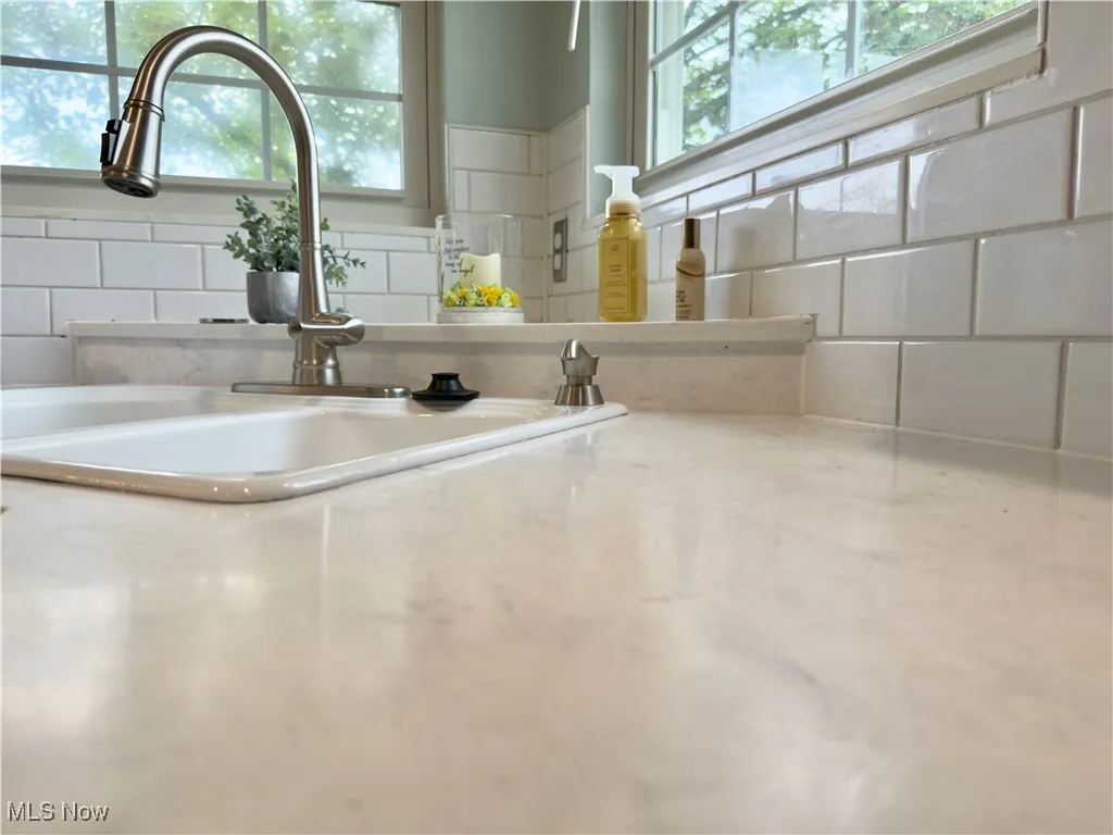Kitchen view of a sink and tasteful backsplash