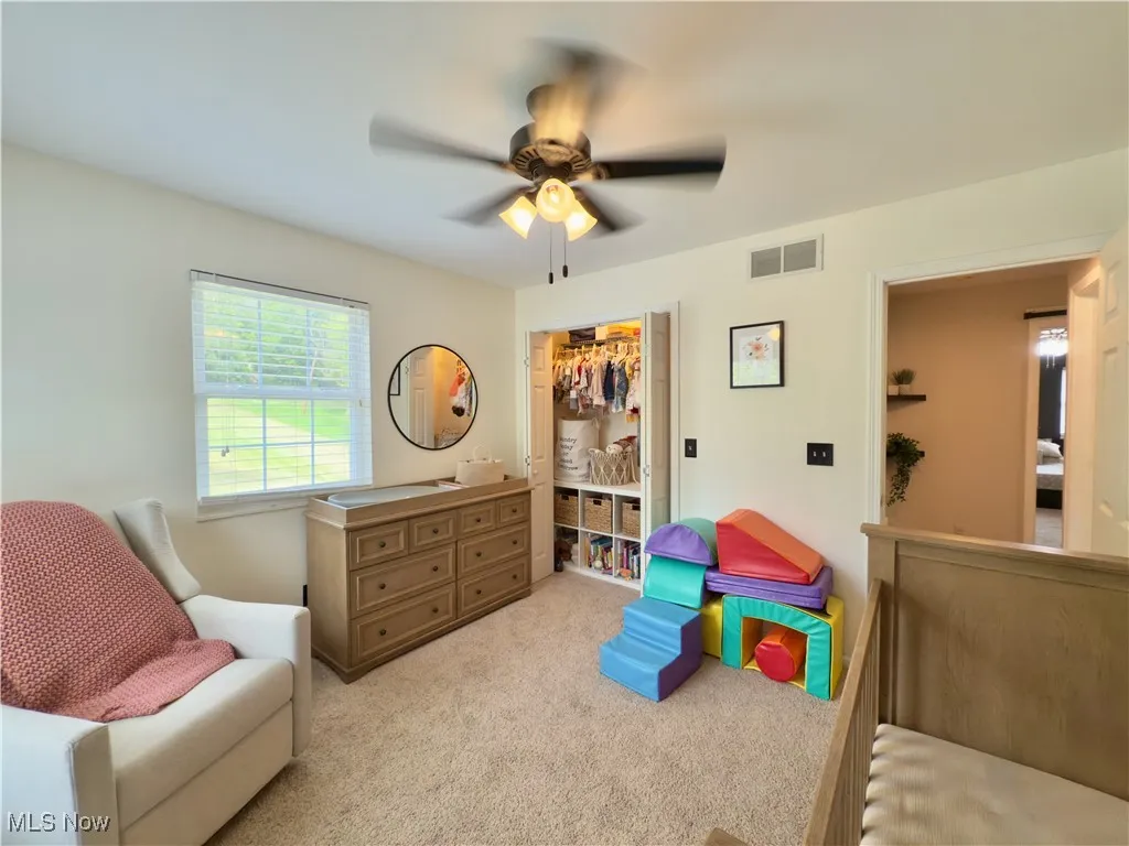 Living area featuring a ceiling fan and light colored carpet