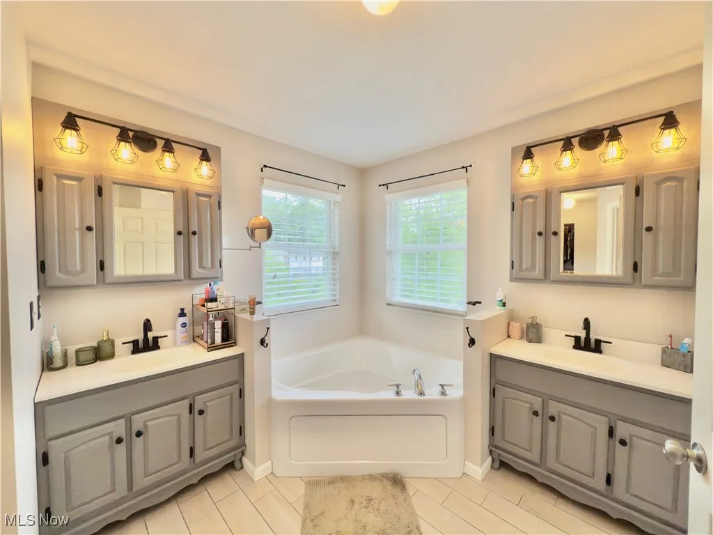 Bathroom featuring a bath, two vanities, and tile patterned floors