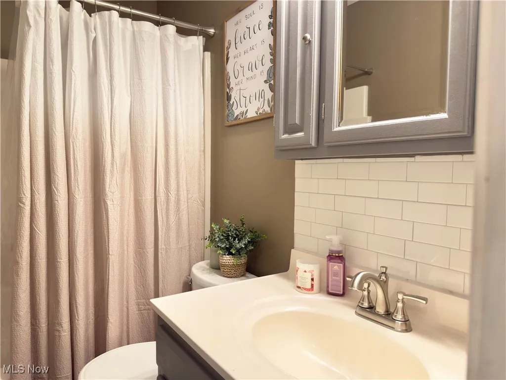 Bathroom with tasteful backsplash, vanity, and a shower with curtain