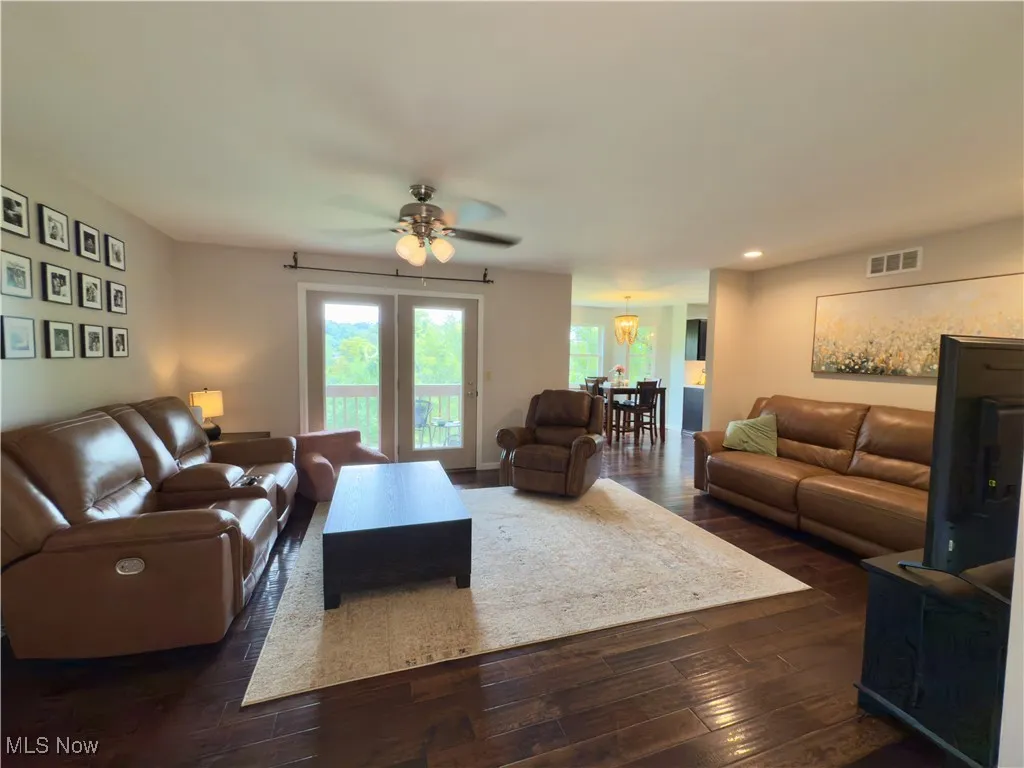 Living room with dark wood finished floors, a ceiling fan, a chandelier, and recessed lighting