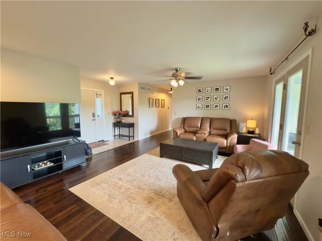 Living area featuring dark wood-style floors and ceiling fan