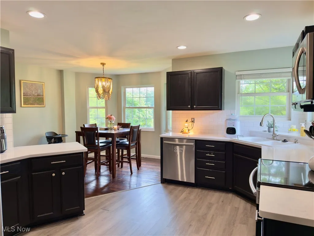Kitchen with backsplash, appliances with stainless steel finishes, recessed lighting, light countertops, and light wood-type flooring