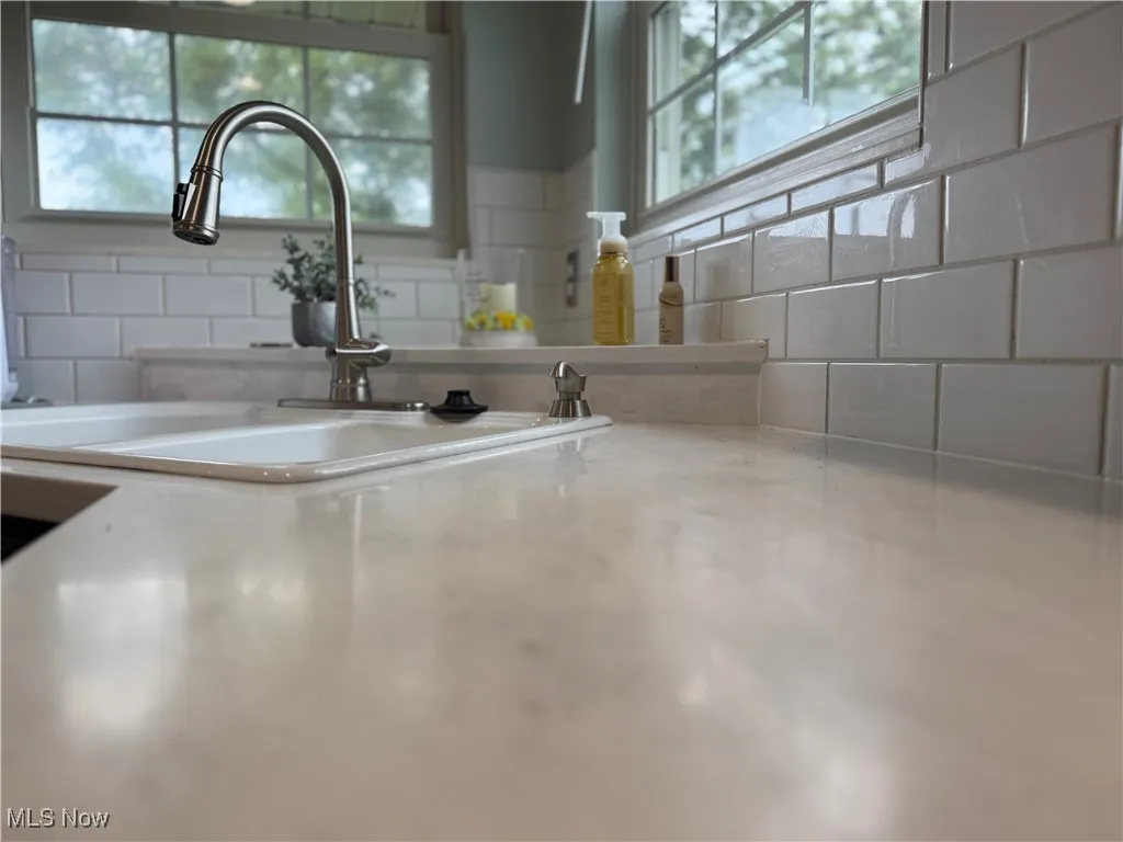 Kitchen view of light countertops and decorative backsplash
