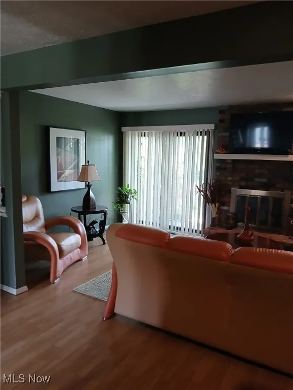 Living room with a fireplace, wood finished floors, and a textured ceiling