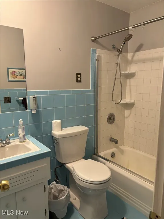 Bathroom featuring tile walls, vanity, shower / bathtub combination, a wainscoted wall, and tile patterned flooring