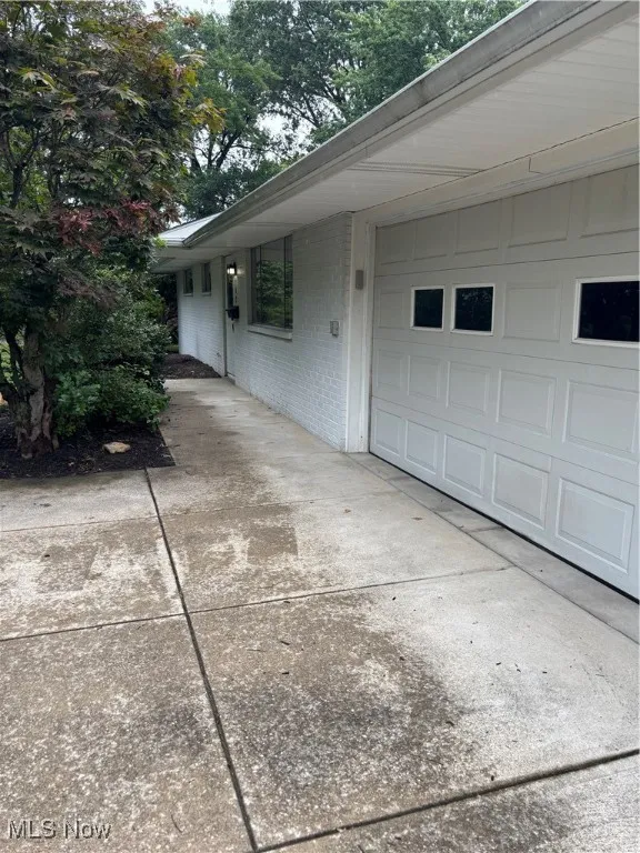 View of home's exterior with brick siding, an attached garage, and driveway
