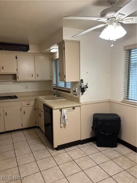 Kitchen featuring light countertops, light tile patterned floors, a ceiling fan, and dishwashing machine
