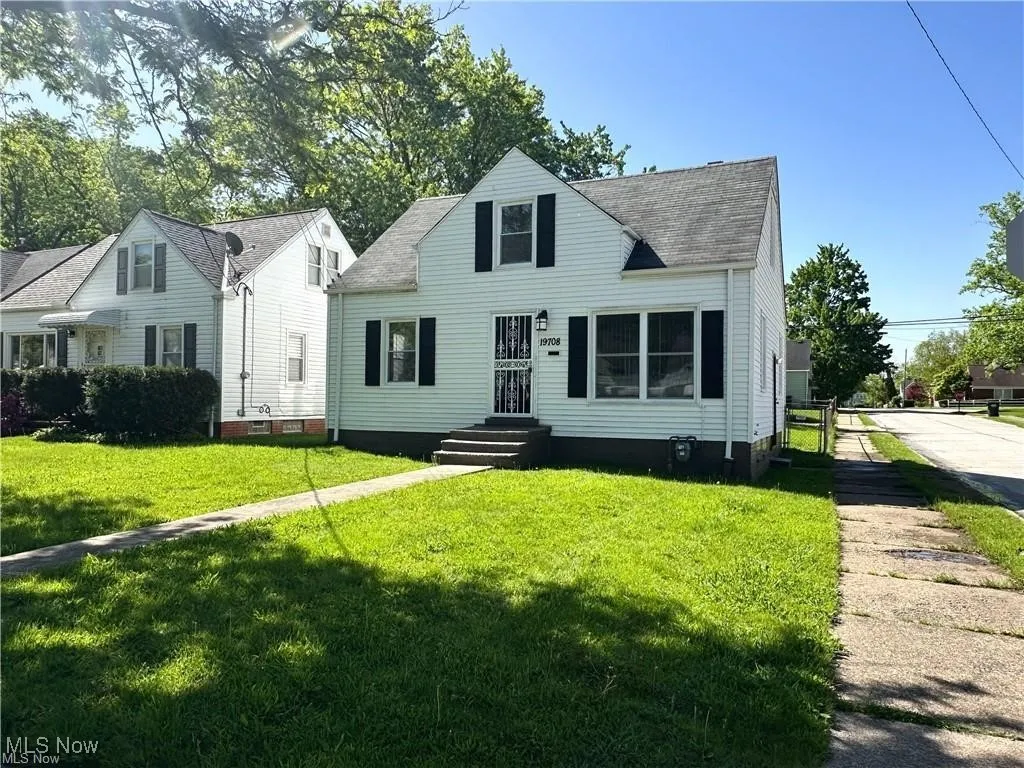 Cape cod house featuring a shingled roof and a front lawn