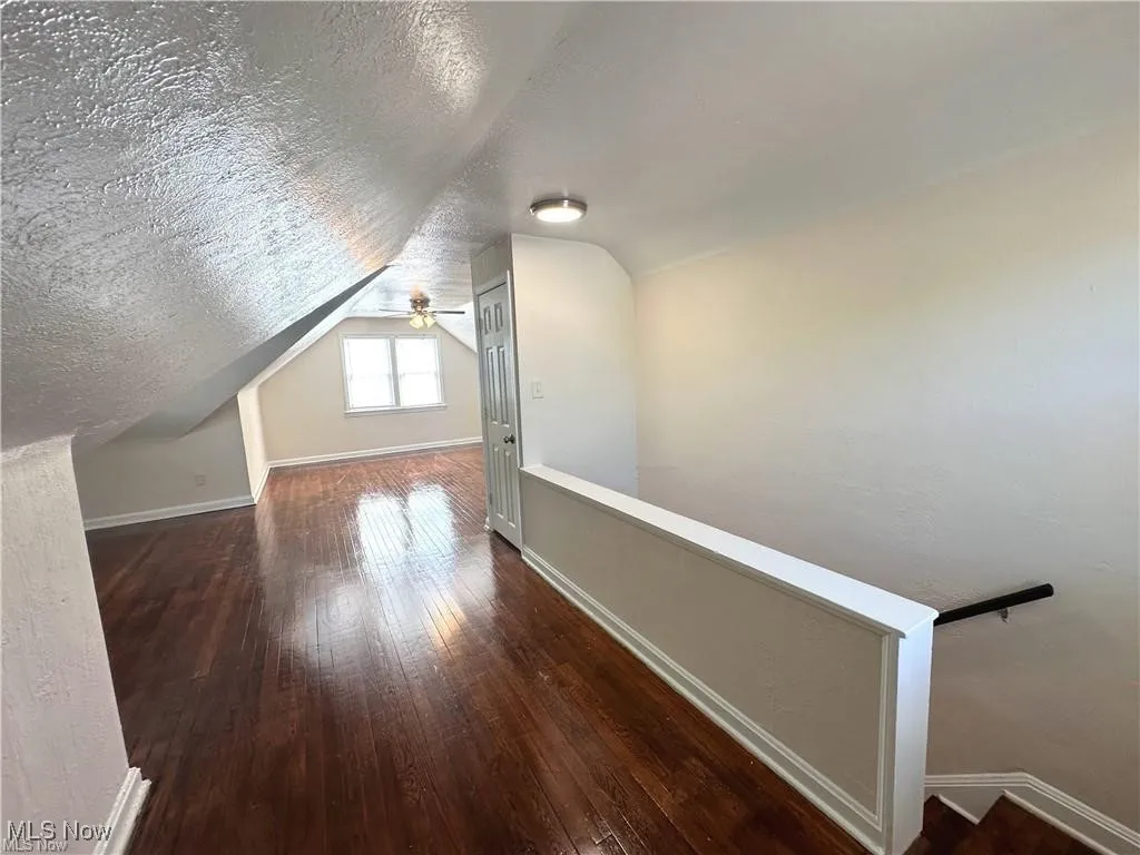 Bonus room featuring a textured ceiling, wood-type flooring, and vaulted ceiling