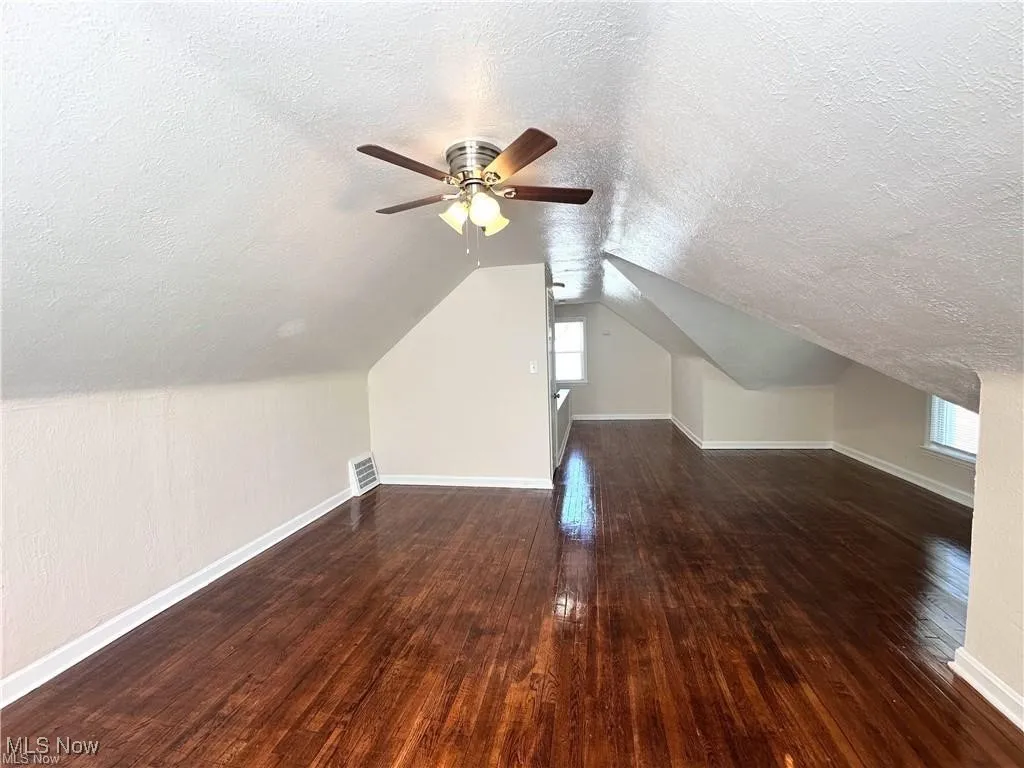 Bonus room with a textured ceiling, hardwood / wood-style flooring, a ceiling fan, and lofted ceiling