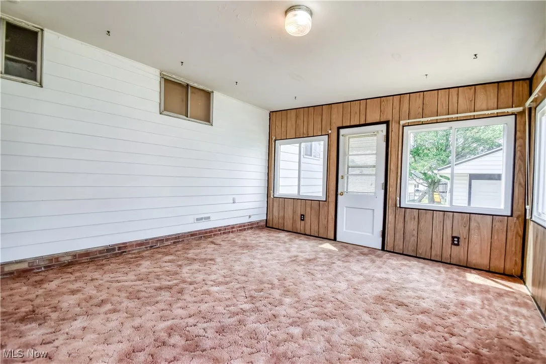 Carpeted spare room featuring wood walls