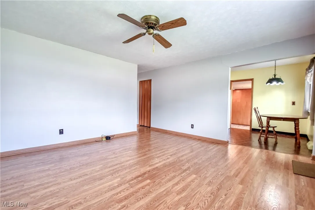 Unfurnished living room with wood finished floors and a ceiling fan