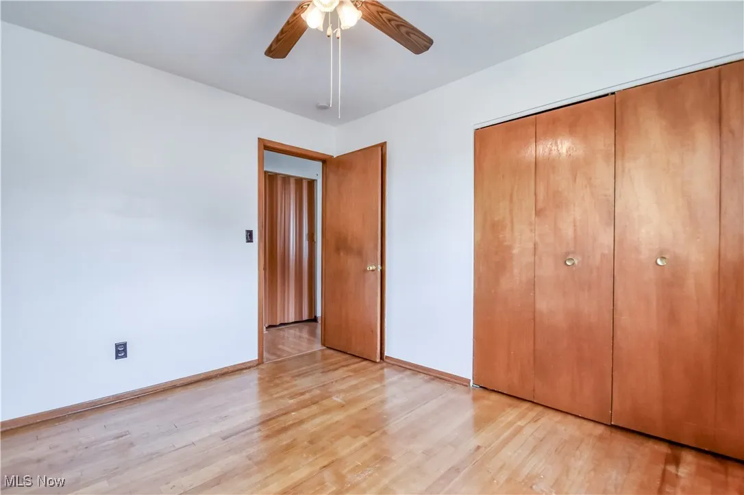 Unfurnished bedroom with light wood-style floors, a closet, and a ceiling fan