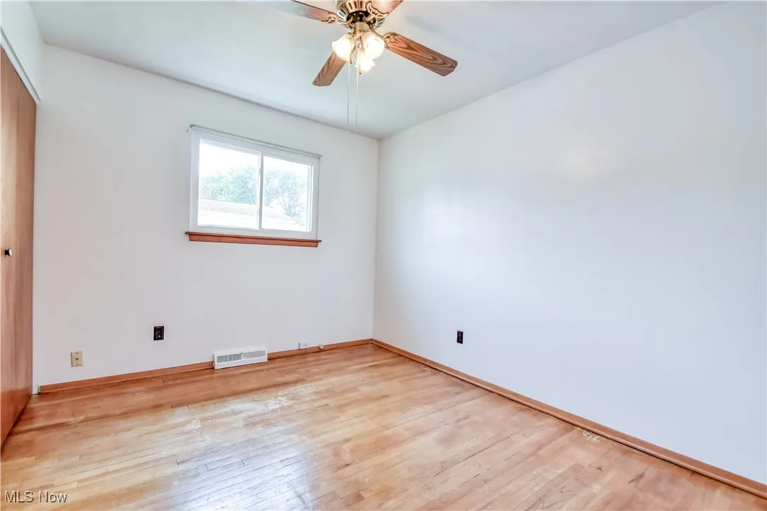 Unfurnished bedroom with wood-type flooring, a closet, and a ceiling fan