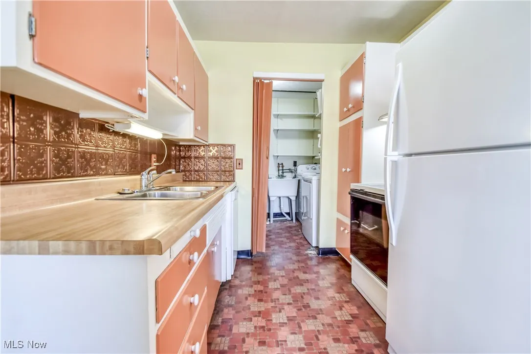 Kitchen featuring white appliances, tasteful backsplash, light countertops, tile patterned floors, and washer / clothes dryer