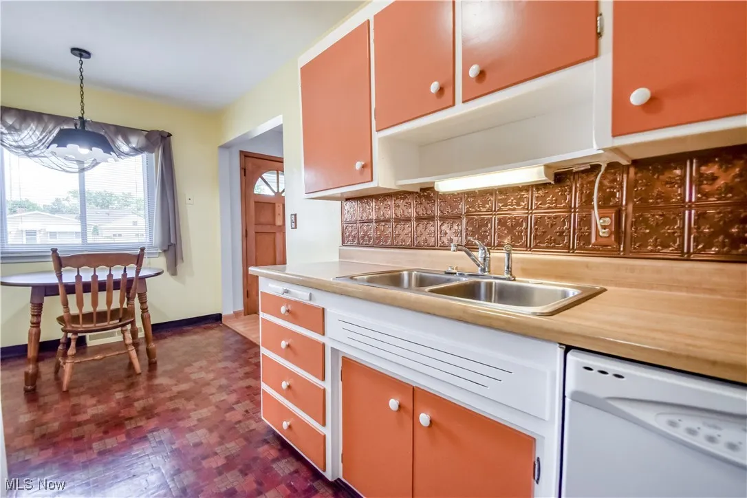 Kitchen with decorative backsplash, dishwasher, light countertops, and hanging light fixtures