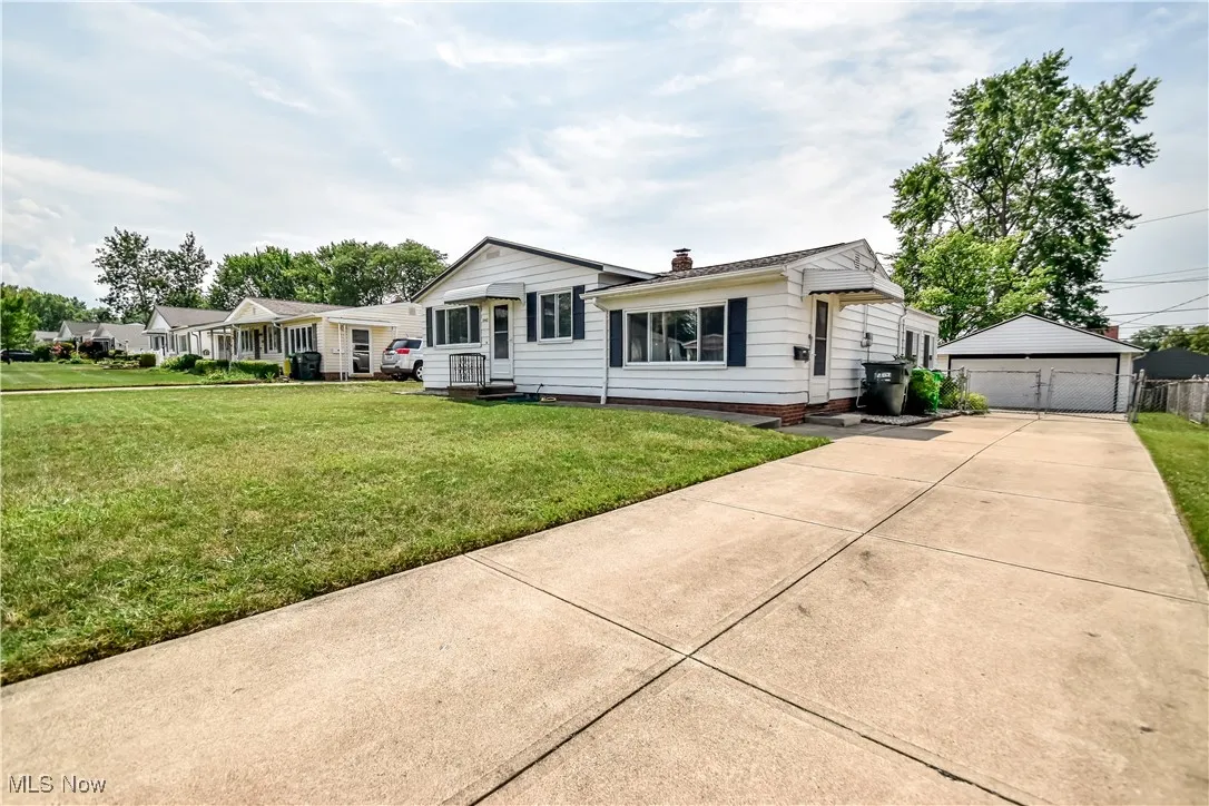 Ranch-style home featuring an outbuilding, a detached garage, a front lawn, and a chimney