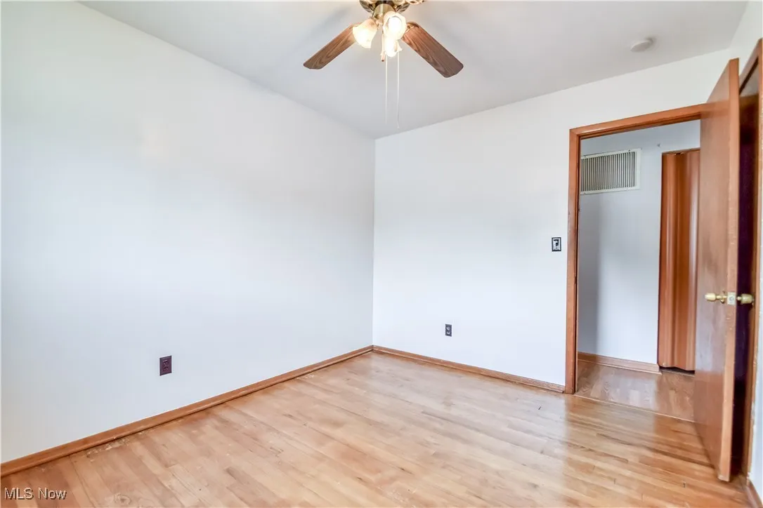 Empty room with light wood-style floors and a ceiling fan