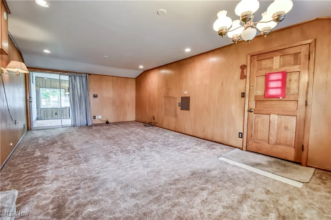 Carpeted entrance foyer featuring wood walls, a chandelier, and recessed lighting