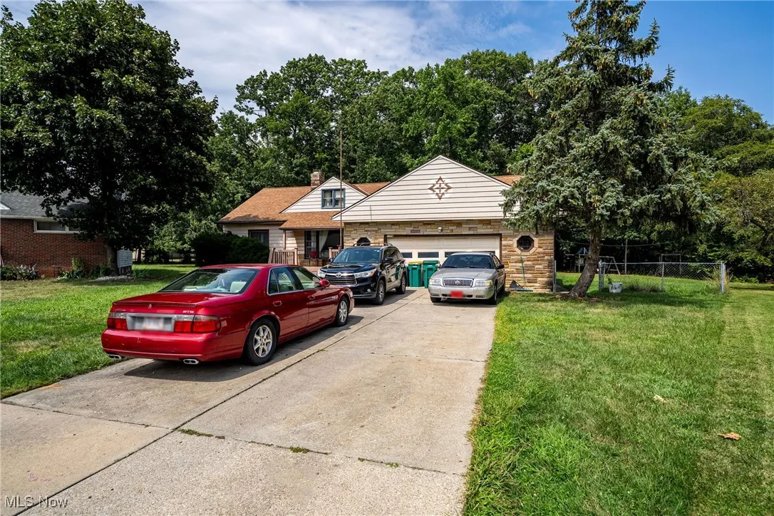 View of front of house with a front yard, driveway, a chimney, and an attached garage