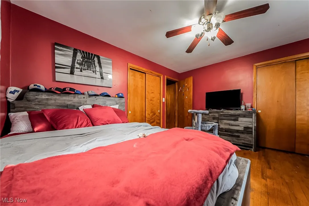 Bedroom with wood-type flooring, multiple closets, and a ceiling fan