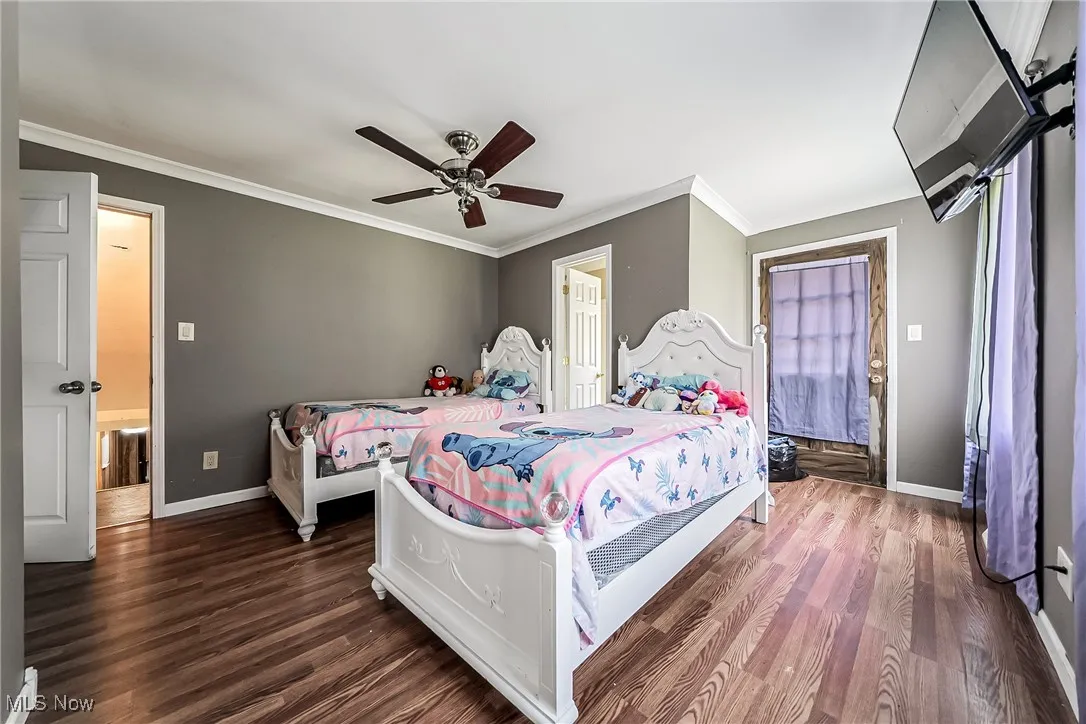 Bedroom featuring crown molding, wood finished floors, and a ceiling fan