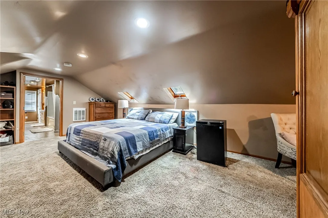 Bedroom featuring light carpet, a skylight, lofted ceiling, recessed lighting, and ensuite bath