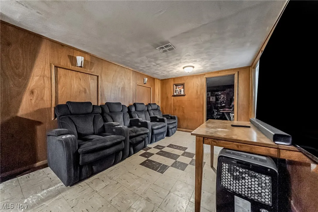 Cinema with wood walls, light floors, and a textured ceiling