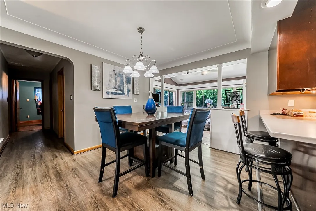 Dining area with light wood-style flooring, a chandelier, and arched walkways
