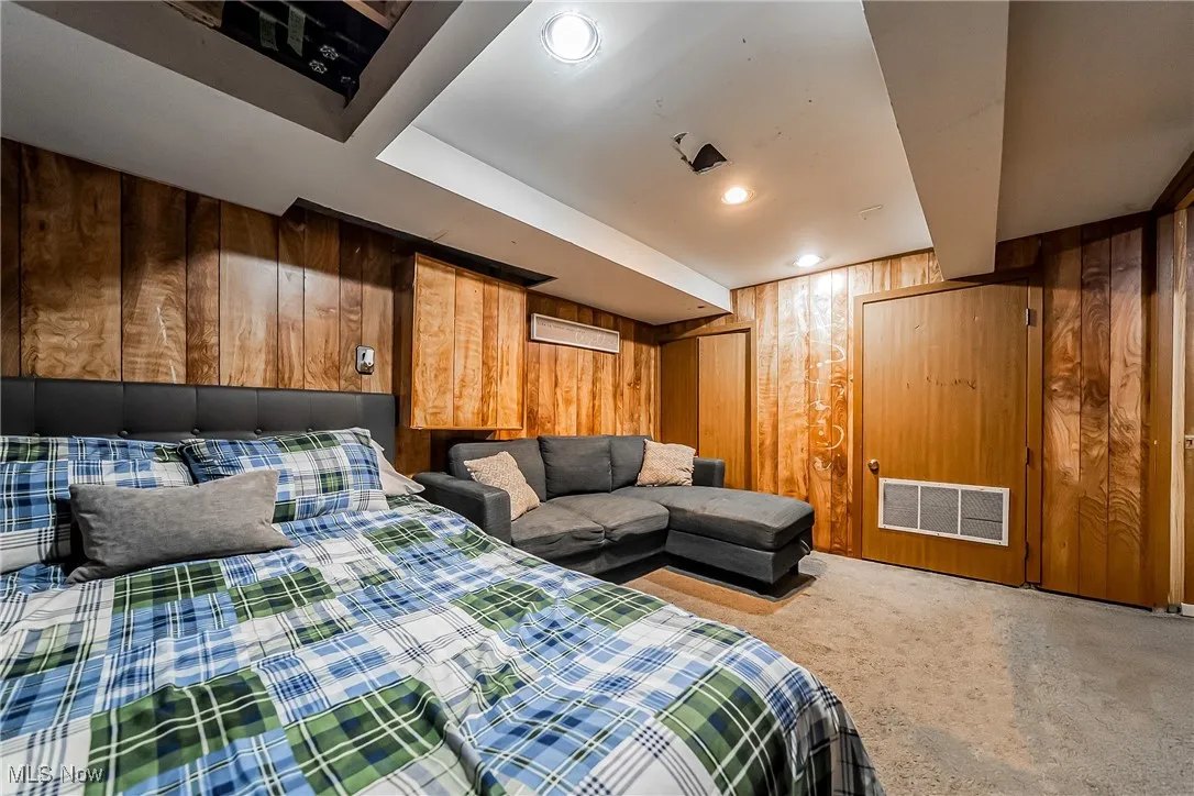 Bedroom with wooden walls, carpet, and recessed lighting