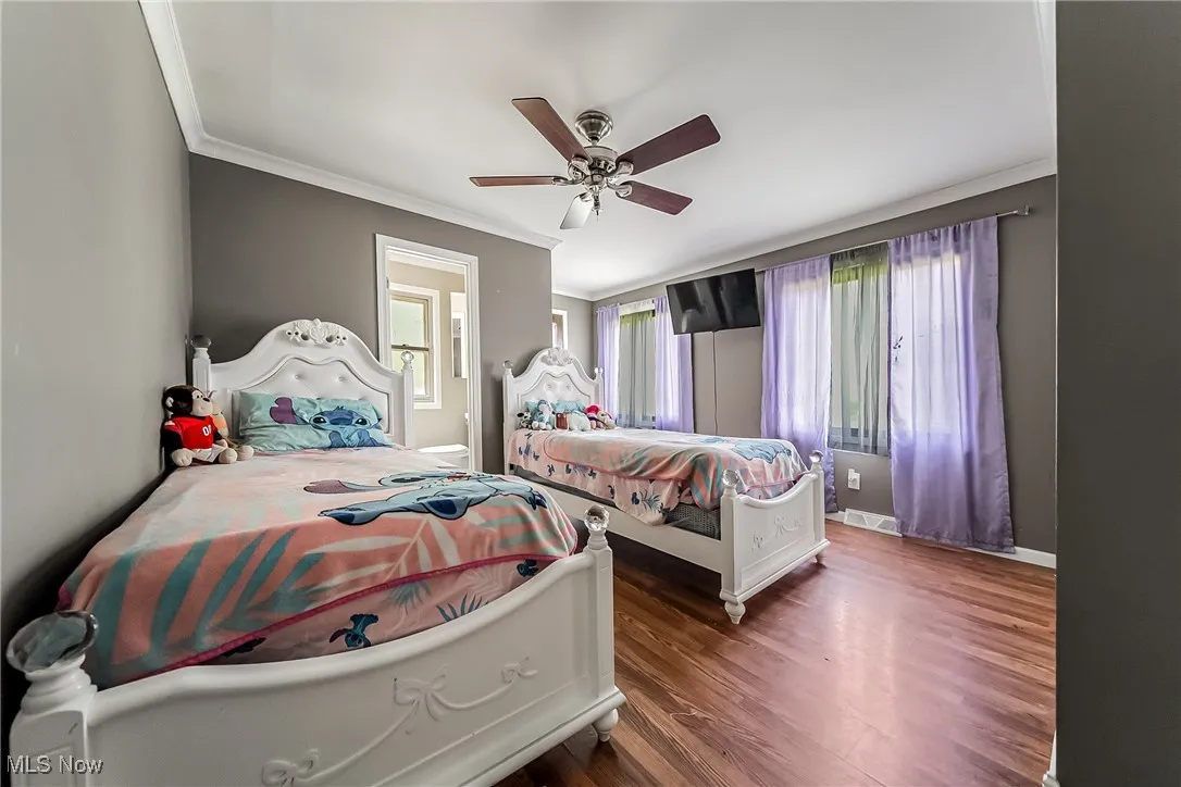 Bedroom featuring ornamental molding, wood finished floors, connected bathroom, and ceiling fan