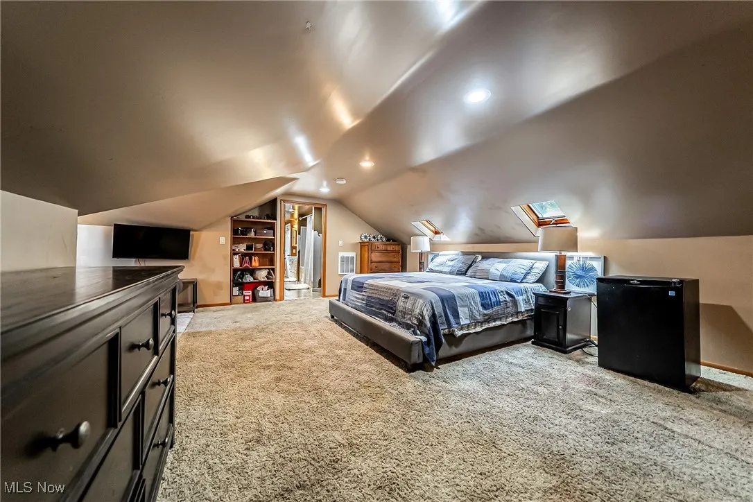 Bedroom with carpet flooring, a skylight, and lofted ceiling
