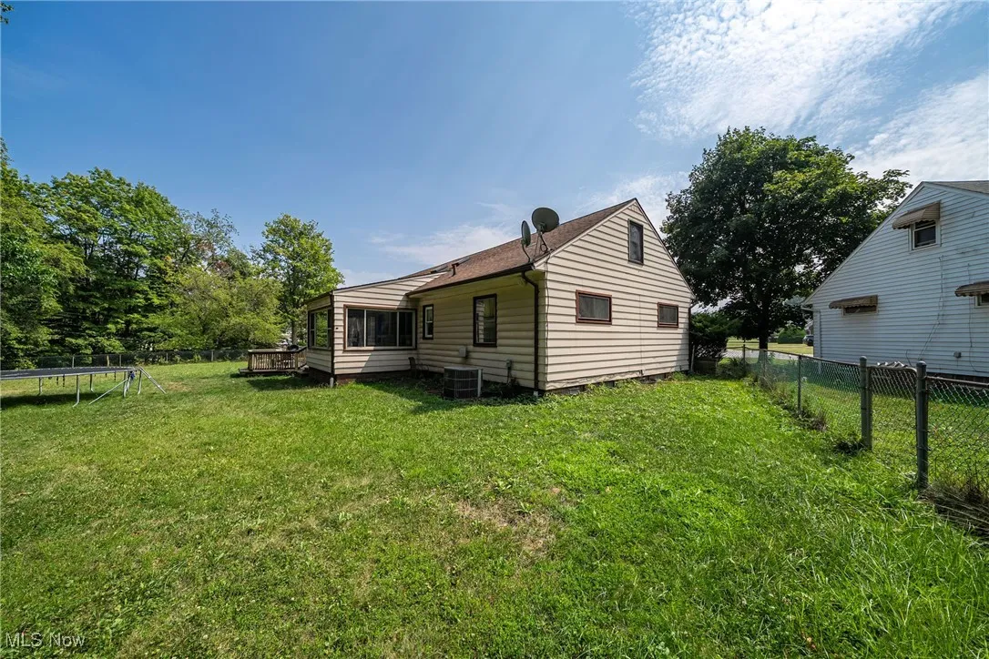Rear view of property featuring a trampoline and a fenced backyard